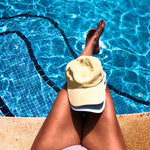 Ellastiek model bij het zwembad met een gele en blauwe pet